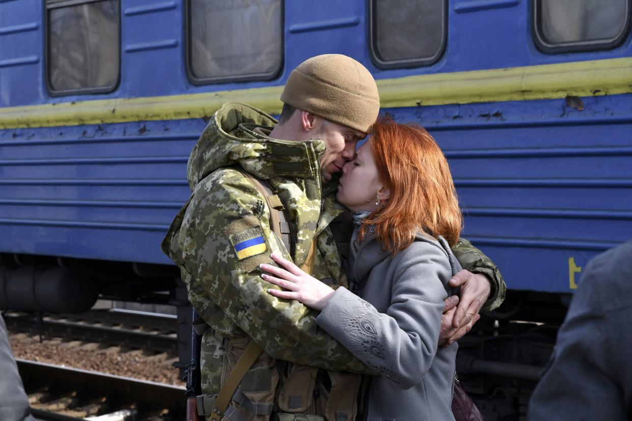 A couple embrace prior to the woman boarding a train carriage leaving for western Ukraine at the railway station in Kramatorsk, eastern Ukraine, Sunday, Feb. 27, 2022.