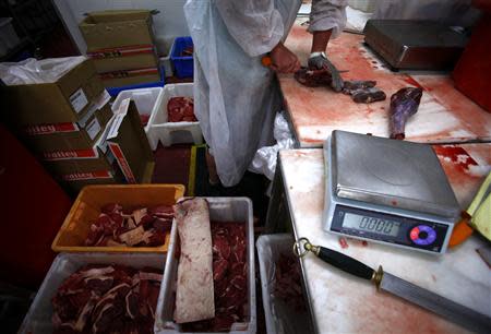 Butcher Trevor Hart cuts up kangaroo meat next to cuts of beef steaks at a meat packing and distribution warehouse in western Sydney November 6, 2013. REUTERS/David Gray