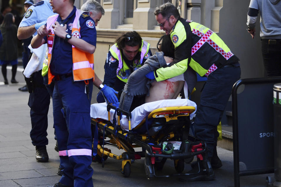 An injured woman is taken by ambulance from Hotel CBD at the corner of King and York Street in Sydney, Australia Tuesday, Aug. 13, 2019. Police and witnesses say a young man yelling about religion and armed with a knife has attempted to stab several people in downtown Sydney before being arrested, with one woman taken to a hospital. (Dean Lewins/AAP Image via AP)