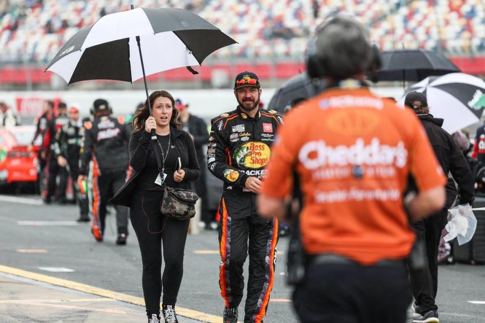 NASCAR Cup Series driver Martin Truex Jr. is escorted away from his car with an umbrella as a rain delay briefly stops the Coca-Cola 600 on Monday, May 29, 2023 at Charlotte Motor Speedway.