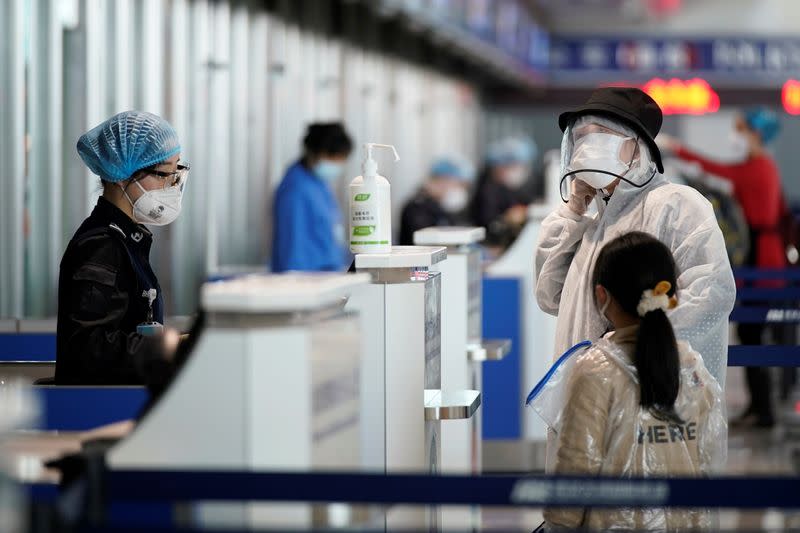 Travellers wearing protective gear are seen at a check-in counter at the Wuhan Tianhe International Airport