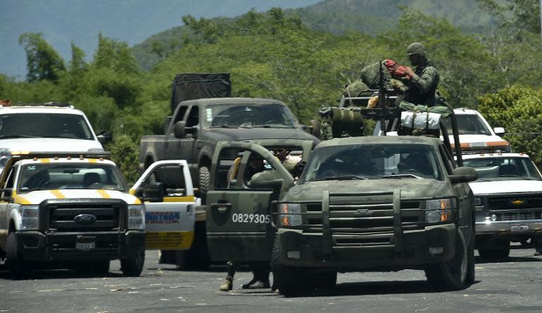 Soldiers stand guard as vehicles involved in a fight with Mexican army members are removed from the site in Villa Purificacion, Jalisco State, Mexico on May 3, 2015