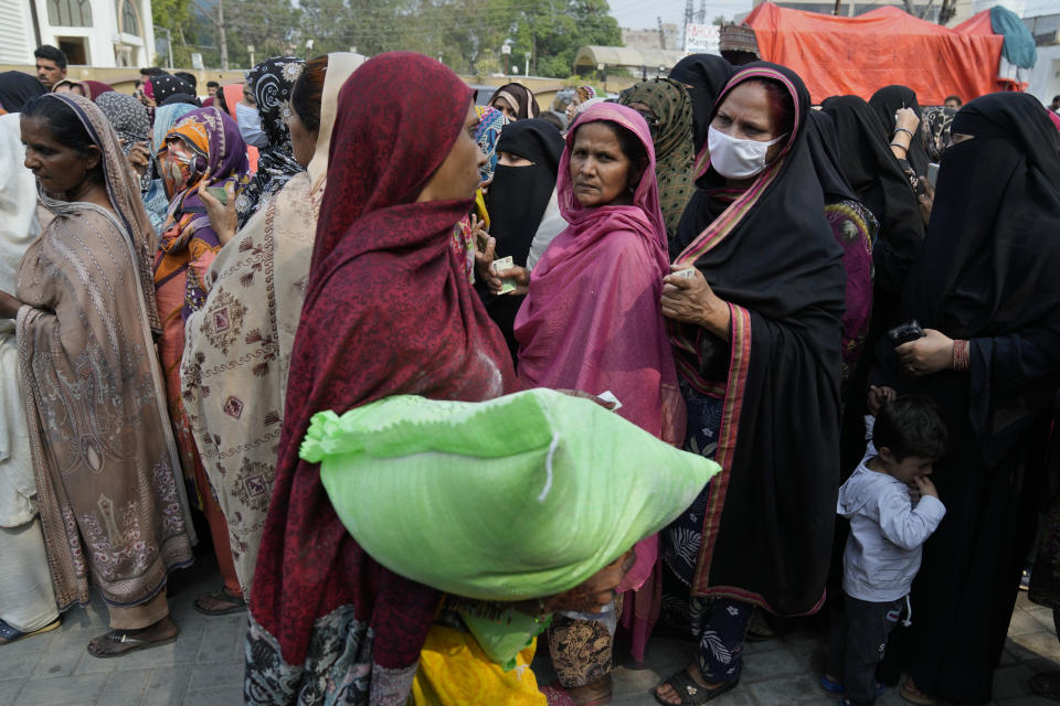 A woman leaves as other wait their turn to get a free sack of wheat flour at a distributing point, in Lahore, Pakistan, Monday, March 20, 2023. Pakistan's Prime Minister Shahbaz Sharif will provide free flour to deserving and poor families during the Muslim's holy month of Ramadan due to high inflation in the country. (AP Photo/K.M. Chaudary)