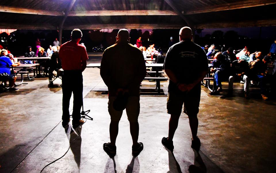 A prayer is offered before a meal served on a Monday night by Under the Bridge Ministry, which offers fellowship, food and basic necessities to people in need. The group meets at Sand Point Park every Monday evening.