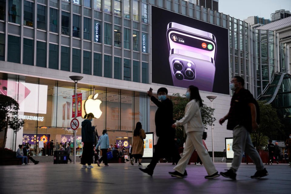 People walk near a display advertising the Apple iPhone 14 outside its store.