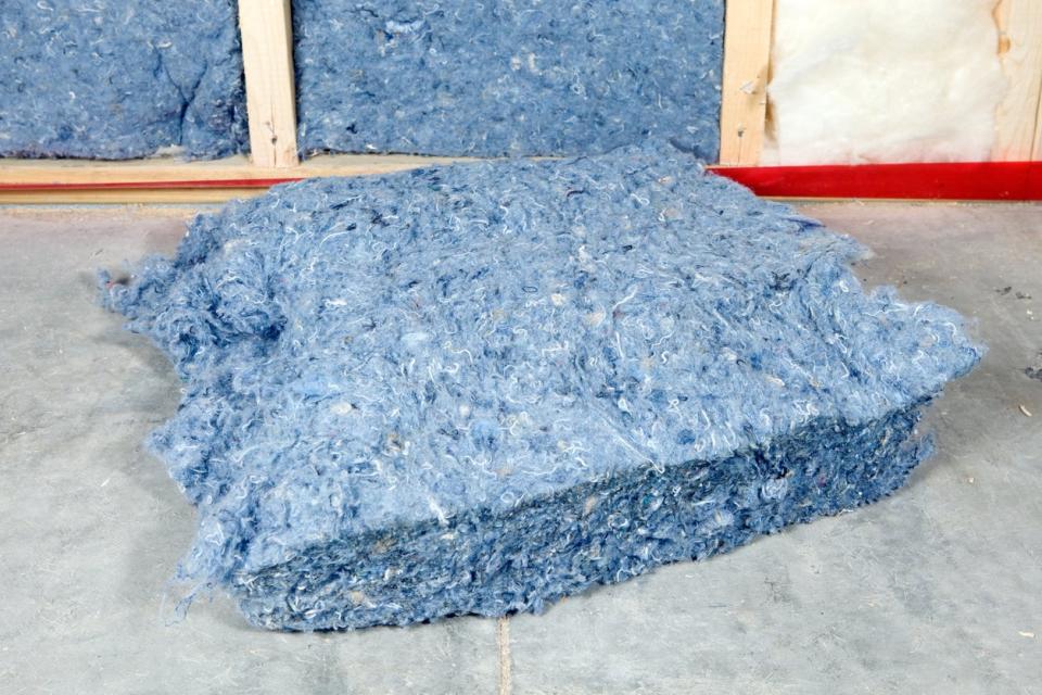 Recycled denim jeans made into home insulation that is being installed in a home. 