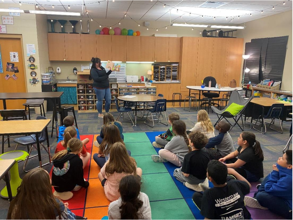 Members of Horizon Bank read about saving money to the students of Sweetwater before having students paint their own piggie bank for the pageant.