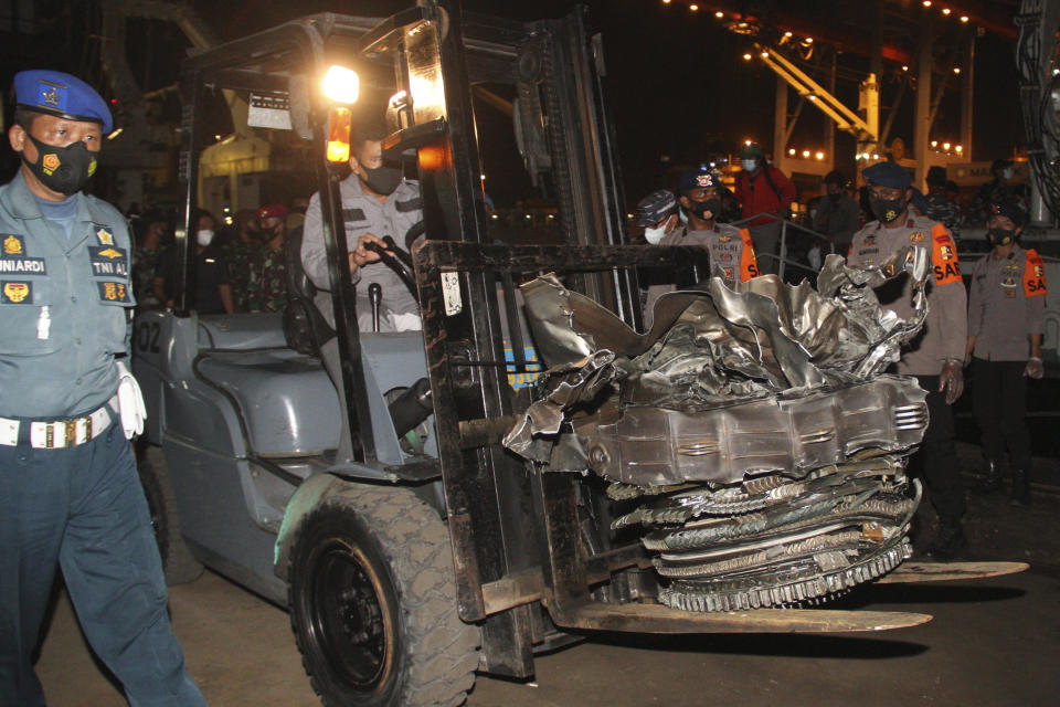 Indonesian navy personnel use a forklift to carry a large part of a plane recovered from the waters off Java Island where a Sriwijaya Air flight SJ-182 crashed on Saturday, at Tanjung Priok Port in Jakarta, Indonesia, late Sunday, Jan. 10, 2021. The search for the black boxes of the crashed Sriwijaya Air jet intensified Monday to boost the investigation into what caused the plane carrying 62 people to nosedive at high velocity into the Java Sea. (AP Photo)