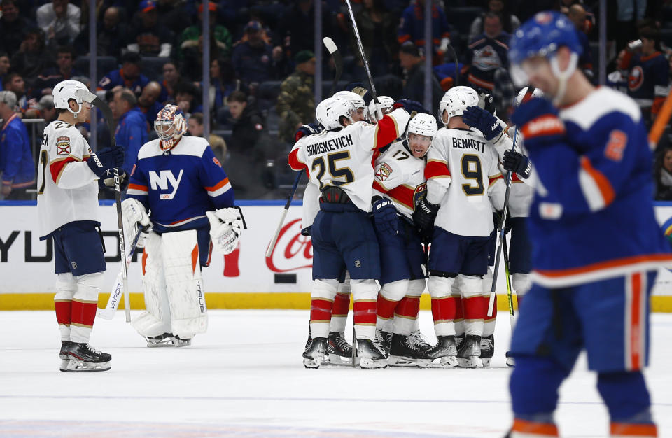 The Florida Panthers celebrate a 3-2 overtime victory as New York Islanders goalie Semyon Varlamov, second from left, skates off the ice after an NHL hockey game Saturday, Jan. 27, 2024, in Elmont, N.Y. (AP Photo/John Munson)