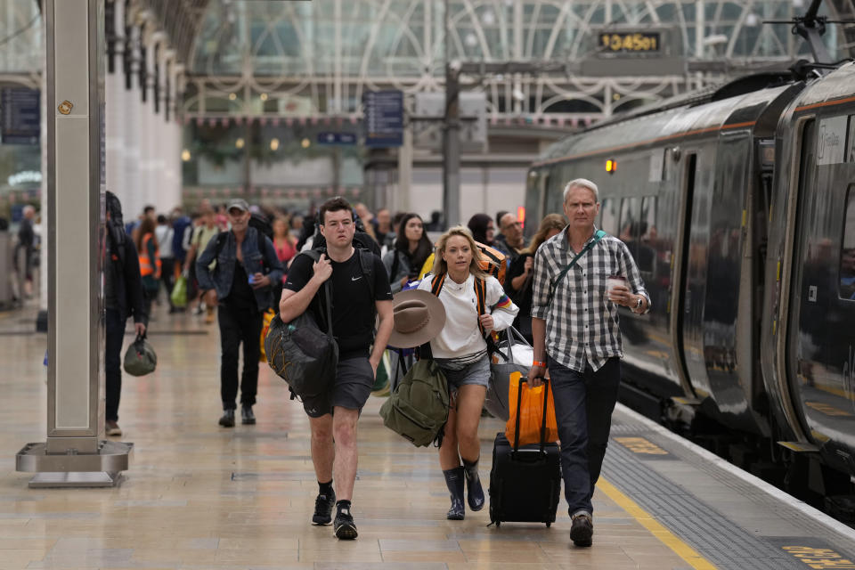 Passengers with camping equipment walk to board a train to go to the Glastonbury music festival at Paddington railway station, in London, during a railway workers strike, Thursday, June 23, 2022. Millions of people in Britain faced disruption Thursday as railway staff staged their second national walkout this week. (AP Photo/Matt Dunham)