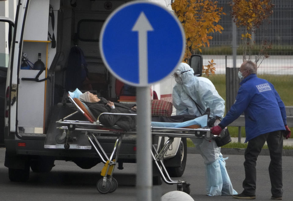 Medical workers carry a patient suspected of having coronavirus on a stretcher at a hospital in Kommunarka, outside Moscow, Russia, Tuesday, Oct. 12, 2021. Russia hit another record of daily coronavirus deaths Tuesday as the country struggled with a rapid surge of infections and lagging vaccination rates, but authorities have been adamant that there would be no new national lockdown. (AP Photo/Alexander Zemlianichenko)