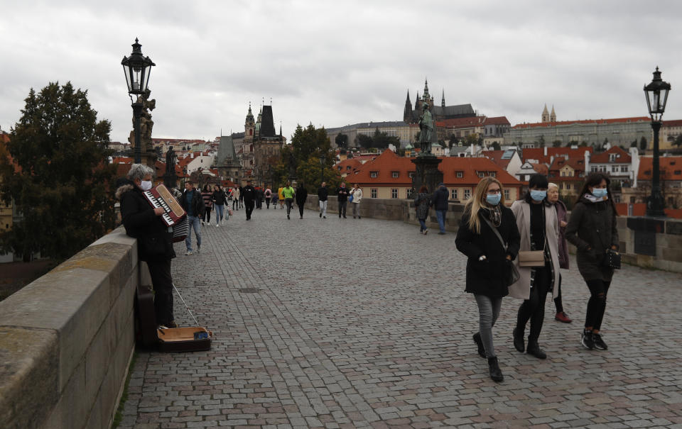 People walk across the medieval Charles Bridge in Prague, Czech Republic, Sunday, Oct. 11, 2020. The Czech Republic and neighboring Slovakia have registered big increases in coronavirus infections, setting a record for the fourth straight day. The government has responded to the record surge by imposing a series of new restrictive measures. Prime Minister Andrej Babis said on Friday he cannot rule out a lockdown of the entire country. (AP Photo/Petr David Josek)