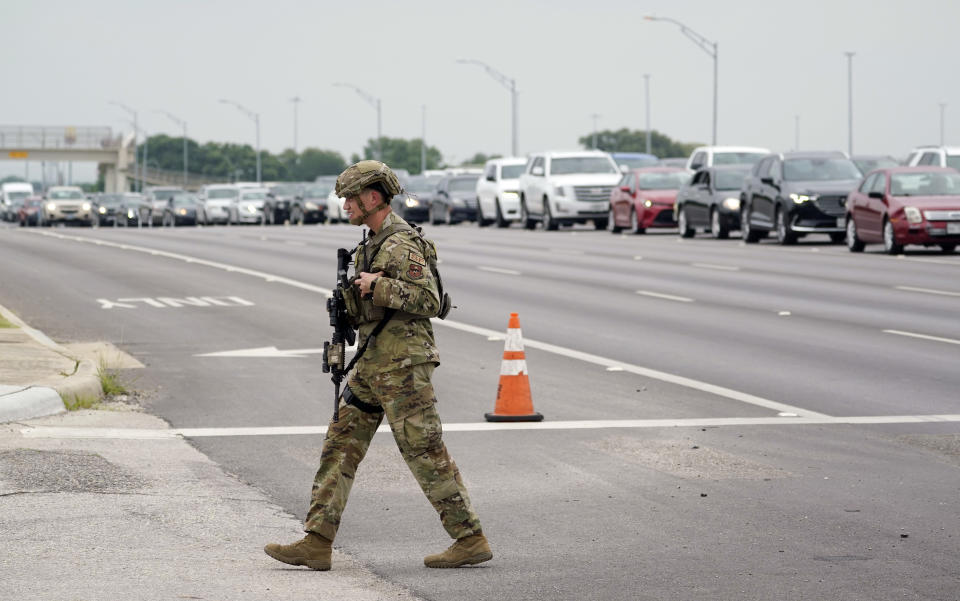 A military policeman walks past traffic outside of a JBSA-Lackland Air Force Base gate, Wednesday, June 9, 2021, in San Antonio. The Air Force was put on lockdown as police and military officials say they searched for two people suspected of shooting into the base from outside. (AP Photo/Eric Gay)