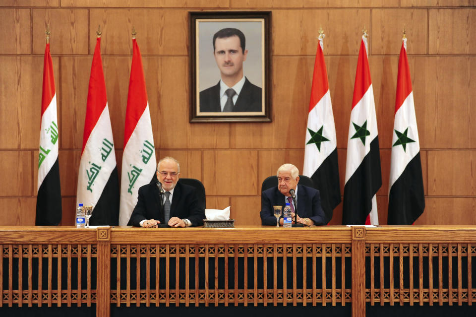 In this photo released by the Syrian official news agency SANA, shows Syrian Foreign Minister Walid al-Moallem, right, speaks during a press conference with his Iraqi counterpart Ibrahim al-Jaafari, in Damascus, Syria, Monday, Oct. 15, 2018. Al-Jaafari said Syria should not be isolated from its Arab neighbors, and lauded Damascus for staying "strong" and united in the face of many adversities. (SANA via AP)