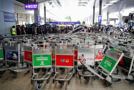 Protesters walk behind barricades at Hong Kong International Airport