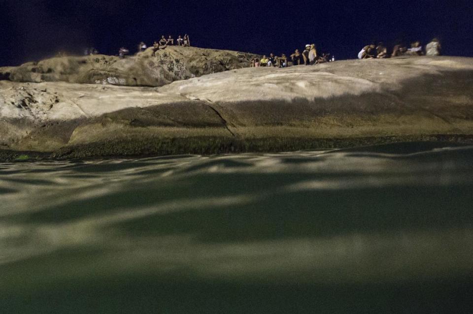 En esta fotografía del 15 de enero de 2017, varias personas se sientan sobre las rocas en la playa Arpoador después de la puesta del sol en Río de Janeiro, Brasil. (AP Foto/Felipe Dana)