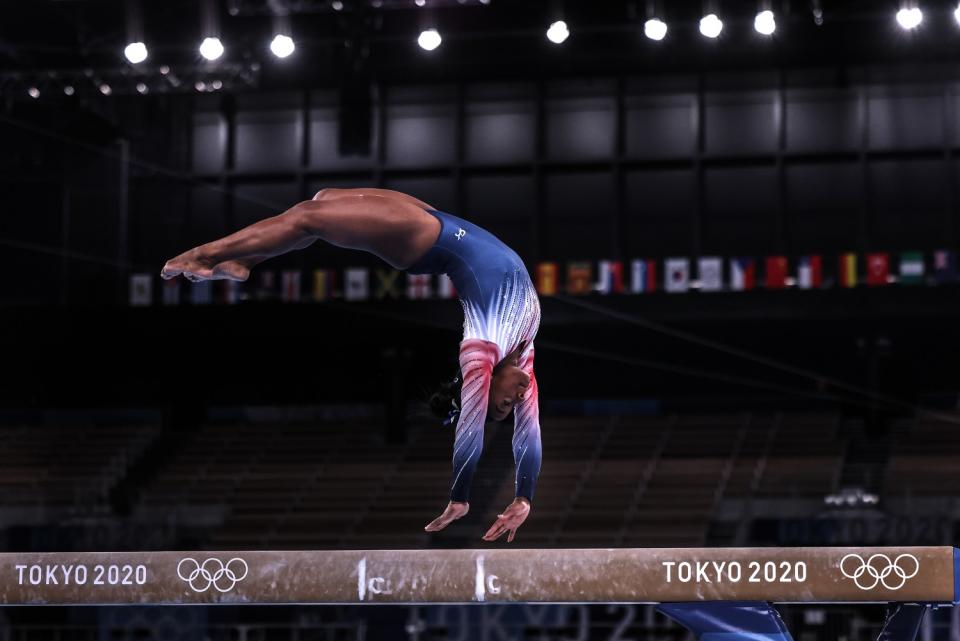 Simone Biles does a back flip on the beam.