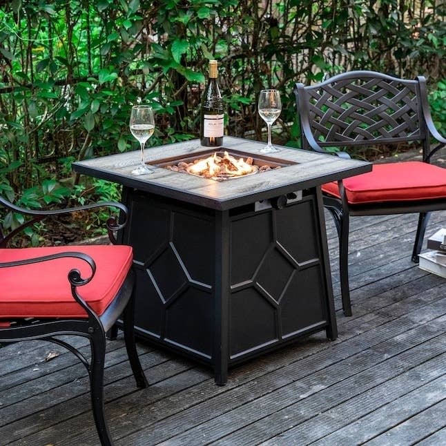 A fire pit holds glasses and a bottle