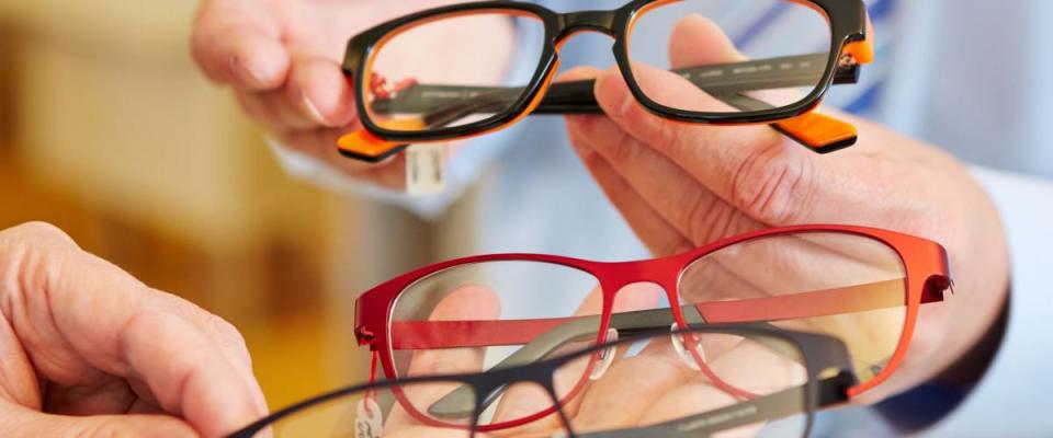 Optician offering a customer a choice of different glasses