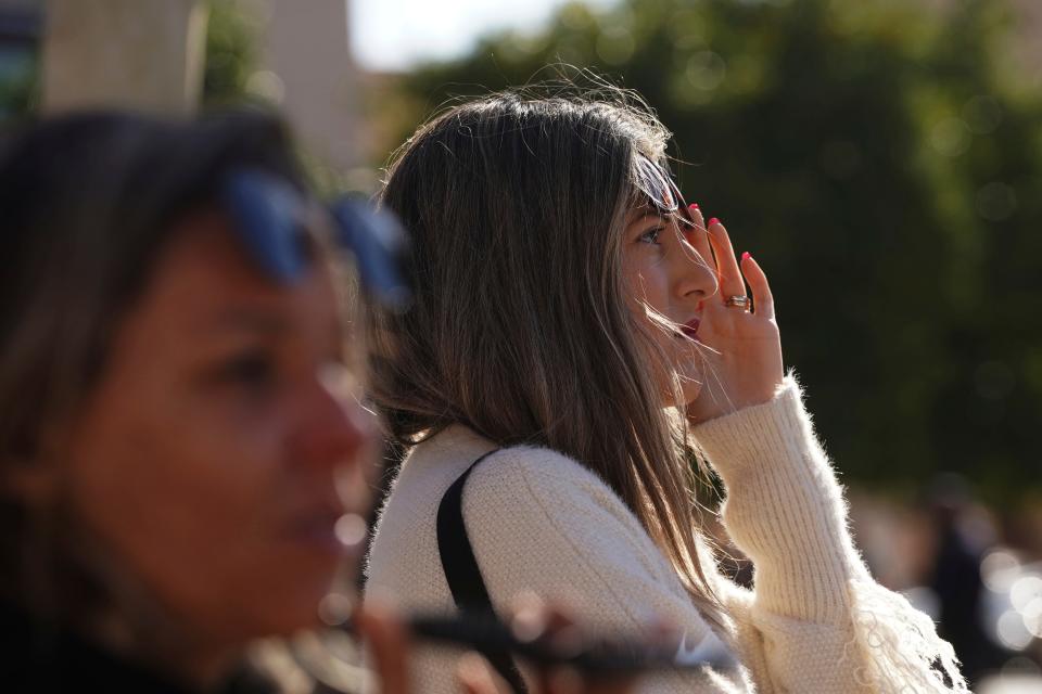 People watch as firefighters work inside a burned block building in Valencia, Spain, Friday, Feb. 23, 2024.