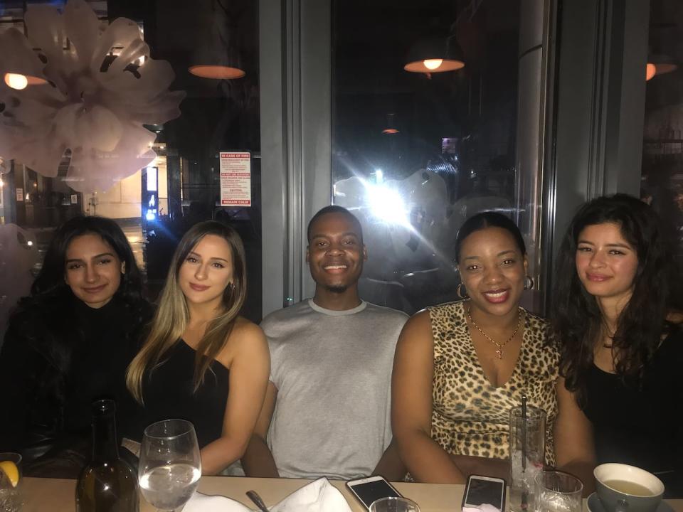 Kemo Montique (centre), is pictured with friends at a restaurant. The 27-year-old is facing deportation despite living in Canada since 2007.
