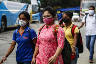 People wearing face masks walk to catch buses in Kolkata, India, Friday, Aug. 14, 2020. India's coronavirus death toll overtook Britain's to become the fourth-highest in the world with another single-day record increase in cases Friday. (AP Photo/Bikas Das)