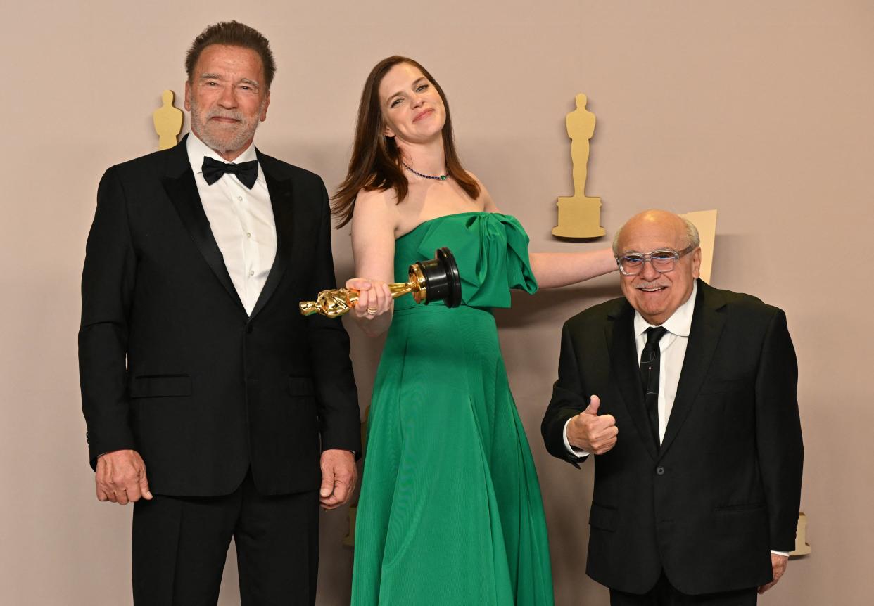 Jennifer Lame poses with Arnlold Schwarzenegger (left) and Danny DeVito (AFP via Getty Images)