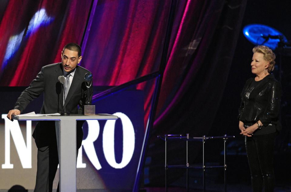 As Bette Midler looks on, right, Gil Bianchini accepts induction into the Rock and Roll Hall of Fame for his late mother, Laura Nyro, Saturday, April 14, 2012, in Cleveland. (AP Photo/Tony Dejak)