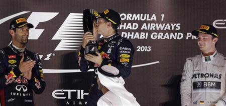 Red Bull Formula One driver Sebastian Vettel of Germany (C) kisses his trophy after winning the Abu Dhabi F1 Grand Prix at the Yas Marina circuit on Yas Island, November 3, 2013. REUTERS/Caren Firouz