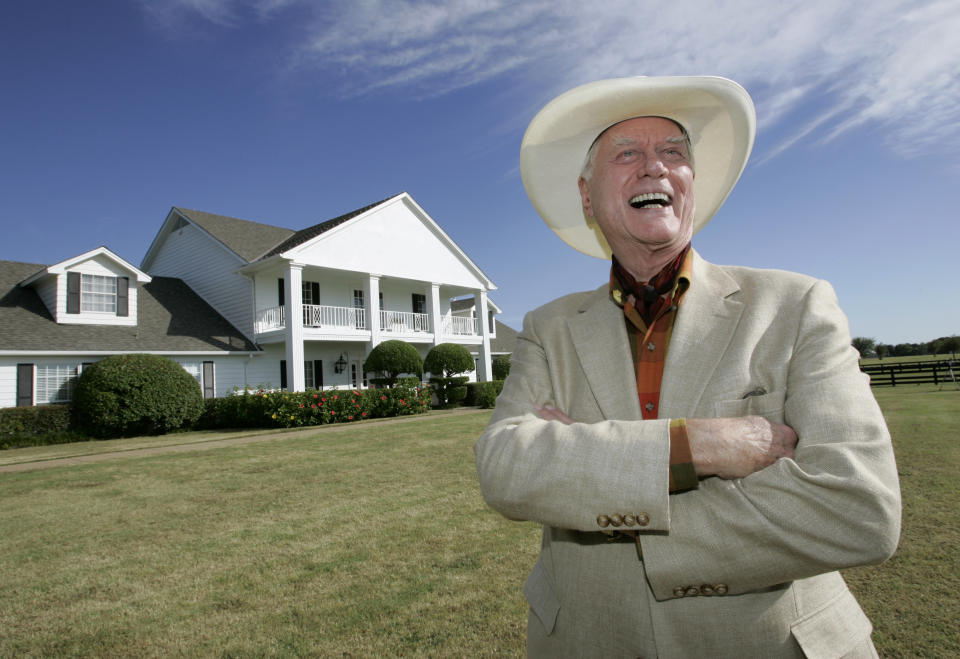 FILE - In this Oct. 9, 2008, file photo, the late Actor Larry Hagman poses in front of the Southfork Ranch mansion made famous in the television show, "Dallas", in Parker, Texas. Tourists have been flocking to Southfork Ranch since the early years of the classic series, which ran from 1978 to 1991. And a new “Dallas” starting its second season on TNT on Monday and the recent death of the show's star, Larry Hagman, who legendarily played conniving Texas oilman J.R. Ewing, have also spurred fans to visit. (AP Photo/Tony Gutierrez, file)