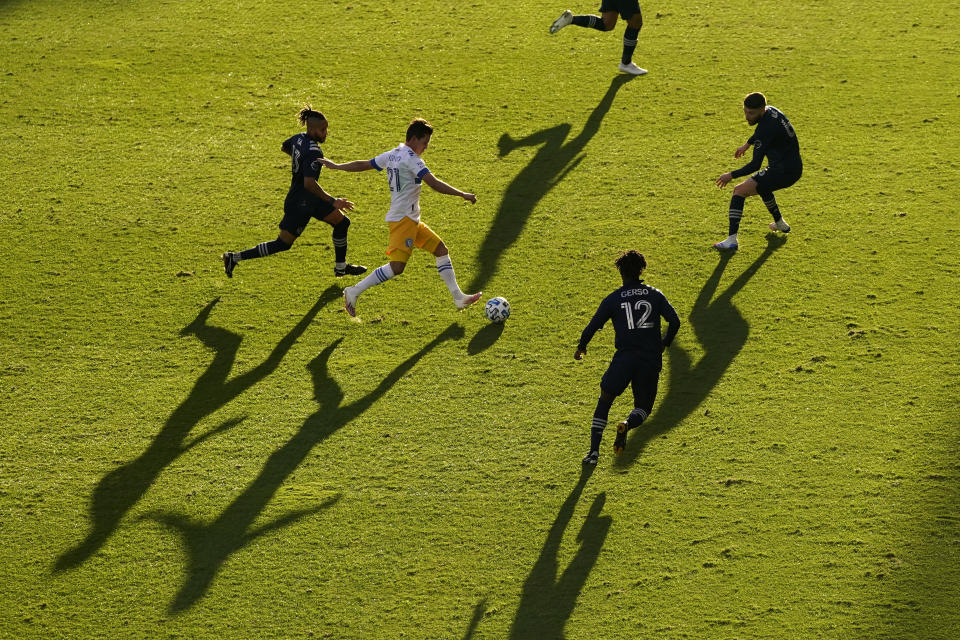 San Jose Earthquakes midfielder Carlos Fierro (21) moves the ball under pressure from a group of Sporting Kansas City players during the first half of an MLS soccer match Sunday, Nov. 22, 2020, in Kansas City, Kan. (AP Photo/Charlie Riedel)