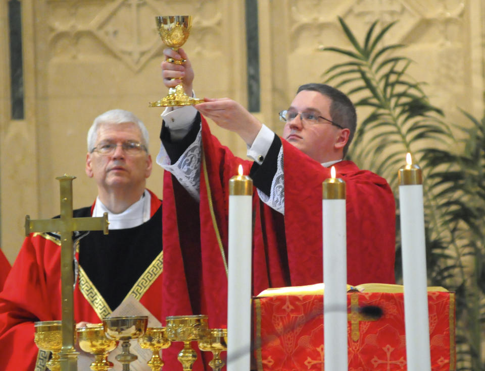 File- This June 8, 2014, file photo shows the Reverend Kevin M. Lonergan, right, who was ordained celebrated his first mass at St. Patrick's Church in Pottsville, Pa. The 30-year-old Lonergan was charged Tuesday, Aug. 21, 2018, with corruption of minors, a felony, and indecent assault. He is facing charges in connection with a 17-year-old girl he met at Mass, including allegations that he sent her nude images of himself on social media and groped her during a hug. (Andy Matsko/The Republican-Herald via AP)