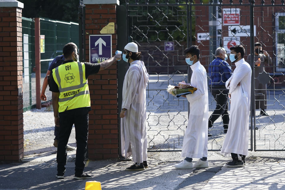 People wearing face masks have their temperatures checked before being allowed to go into Manchester Central Mosque, to try stop the spread of coronavirus, as Muslims worldwide marked the start of the Eid al-Adha holiday, in Manchester, northern England, Friday, July 31, 2020. The British government on Thursday night announced new rules on gatherings in some parts of Northern England, including Manchester, that people there should not mix with other households in private homes or gardens in response to an increase trend in the number of cases of coronavirus cases per 100,000 people. (AP Photo/Jon Super)