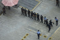 Police officers and security guards prepare for duty outside the headquarters for Evergrande in Shenzhen in southern China, Thursday, Sept. 23, 2021. The Chinese real estate developer whose struggle to avoid defaulting on billions of dollars of debt has rattled global markets says it will pay interest due Thursday to bondholders in China but gave no sign of plans to pay on a separate bond abroad. (AP Photo/Ng Han Guan)