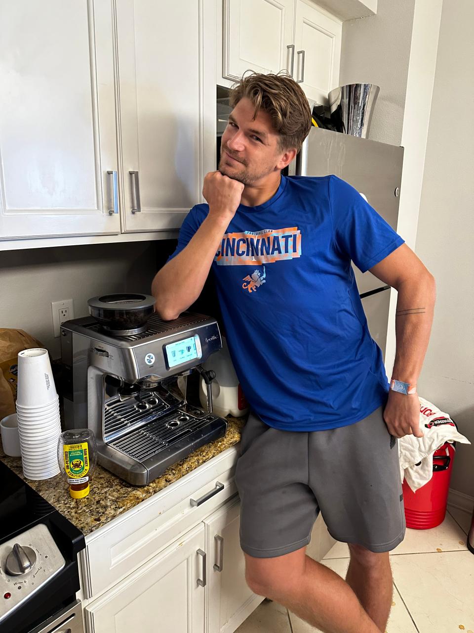Nick Hagglund, an FC Cincinnati defender, poses with a coffee machine that he helps care for and teach others how to use. Hagglund used coffee as a means of bonding with teammates and contributing during preseason in 2024, a time when he was largely sidelined due to injury.