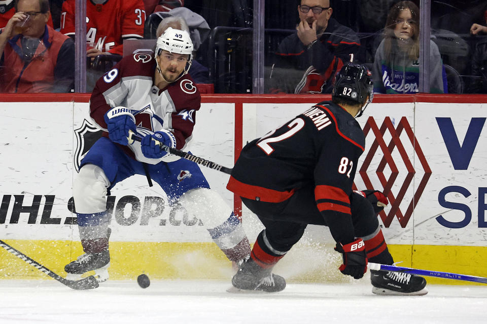 Colorado Avalanche's Samuel Girard (49) clears the puck past Carolina Hurricanes' Jesperi Kotkaniemi (82) during the first period of an NHL hockey game in Raleigh, N.C., Thursday, Feb. 8, 2024. (AP Photo/Karl B DeBlaker)