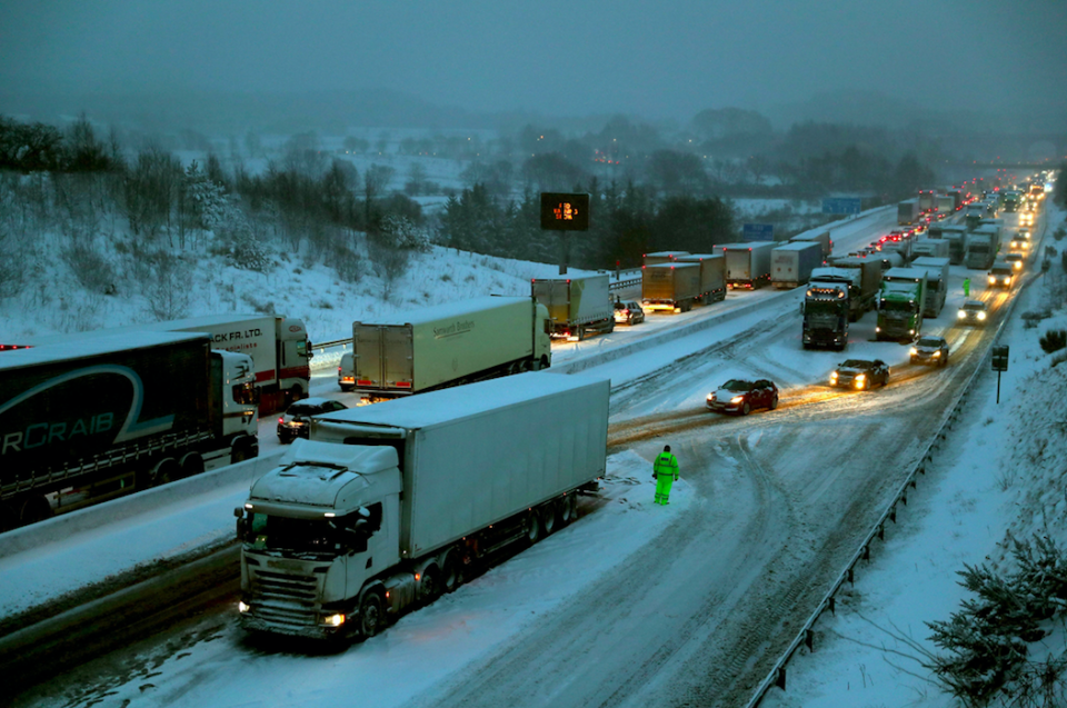 <em>Drivers manoeuvre their cars past stationary lorries on the M80 Haggs in Glasgow (PA)</em>