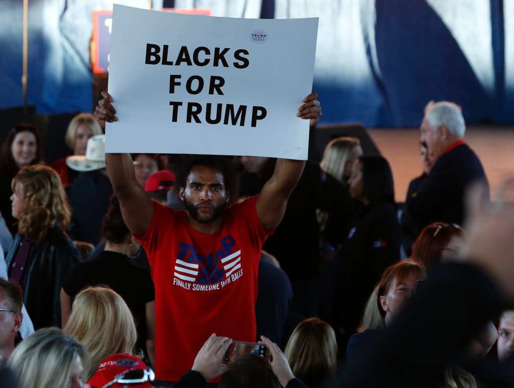 A man holds a “Blacks for Trump” sign on Nov. 6, 2016, as he waits to see then-presidential nominee Donald Trump address supporters at Freedom Hill Amphitheater in Sterling Heights, Michigan. (Photo by Jeff Kowalsky/AFP via Getty Images)