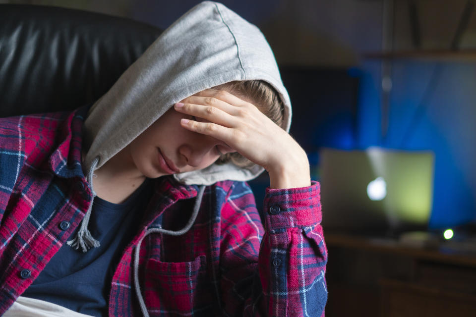 depressed man cover face with palm and sit in chair at night