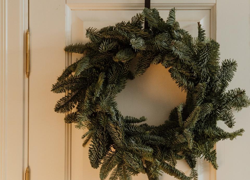 A photo of a evergreen wreath on a white door