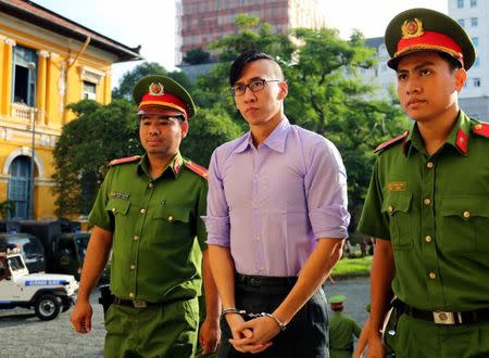 US citizen Will Nguyen (C) is escorted by policemen before his trial at a court in Ho Chi Minh city, Vietnam July 20, 2018. REUTERS/Stringer