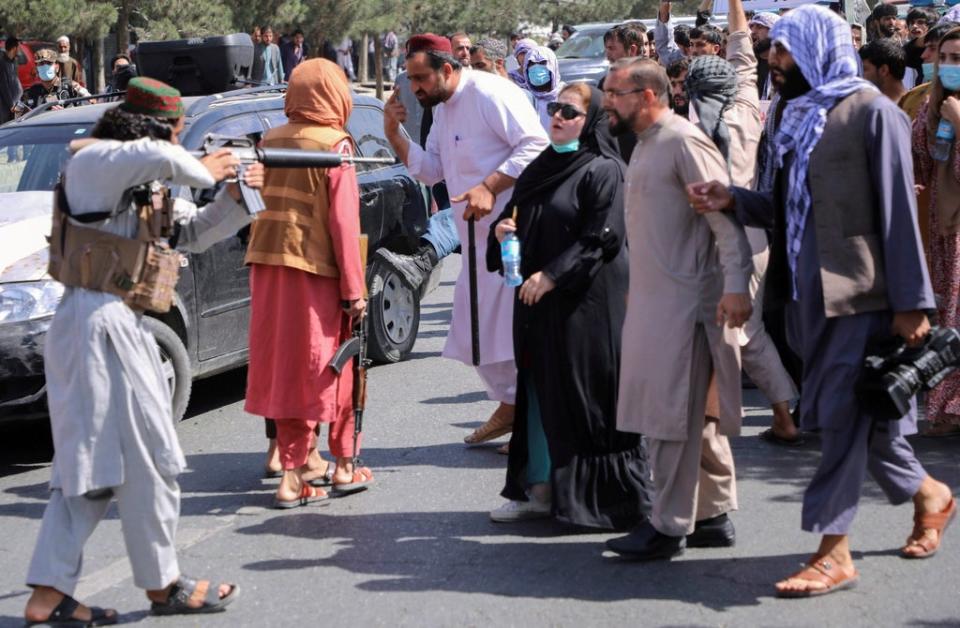 A member of the Taliban forces points his gun at protesters, as Afghan demonstrators shout slogans during an anti-Pakistan protest in Kabul (REUTERS)