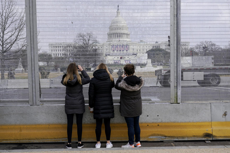 People take photos through the extensive security surrounding the U.S. Capitol in Washington, Friday, Jan. 15, 2021, ahead of the inauguration of President-elect Joe Biden and Vice President-elect Kamala Harris. (AP Photo/Susan Walsh)