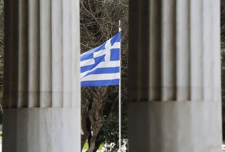 A Greek flag is framed by marble pillars at the Attalos arcade in Athens February 26, 2015. REUTERS/Yannis Behrakis