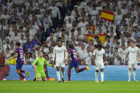 Real Madrid's goalkeeper Andriy Lunin, second left, reacts as Barcelona players celebrate after their teammate Andreas Christensen scores his side's opening goal during the Spanish La Liga soccer match between Real Madrid and Barcelona at the Santiago Bernabeu stadium in Madrid, Spain, Sunday, April 21, 2024. (AP Photo/Manu Fernandez)