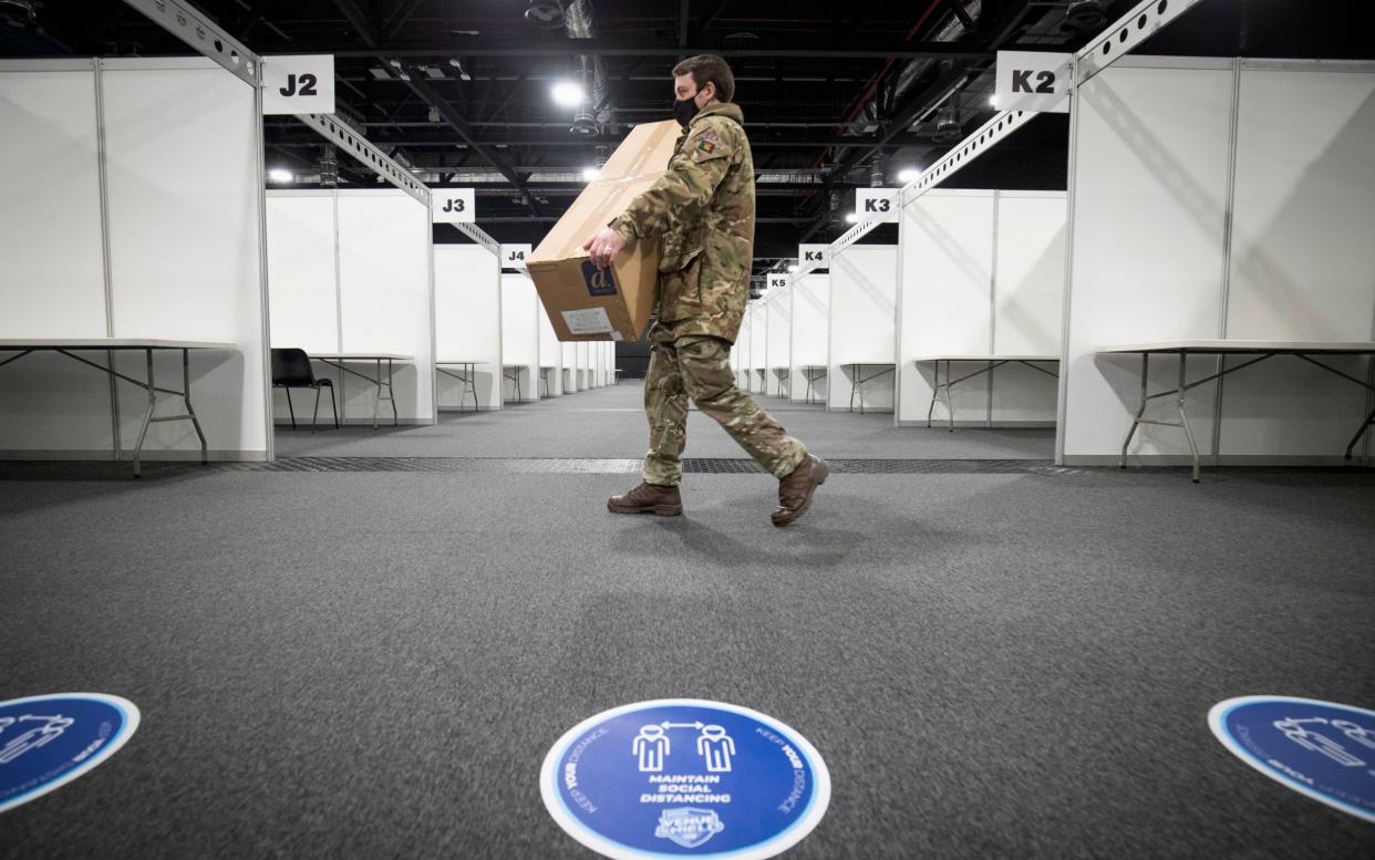 A member of the Royal Scots Dragoon Guard carries in supplies as part of the final preparations setting up a mass Covid vaccination centre - Jane Barlow/PA