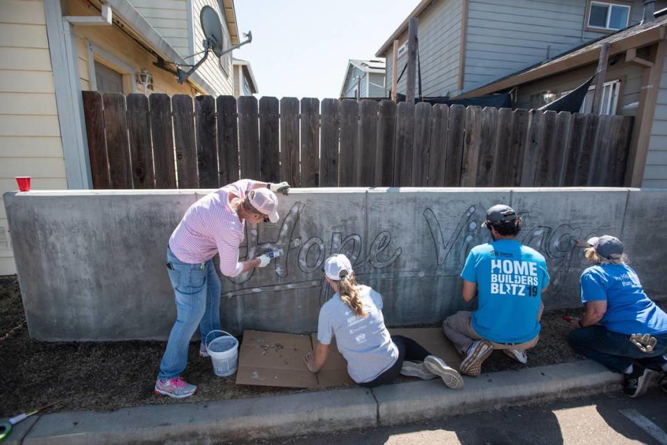 Volunteers repaint a sign at Habitat for Humanity’s Hope Village in Modesto Calif., as part of Love Modesto on Saturday, April 30, 2022.