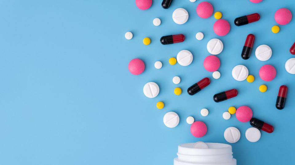 High Angle View Of Pills Spilling Form Bottle On Blue Background