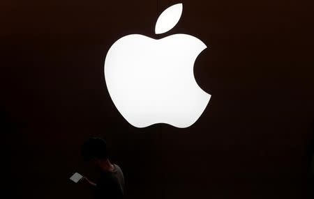 A man looks at the screen of his mobile phone in front of an Apple logo outside its store in Shanghai, China July 30, 2017. REUTERS/Aly Song