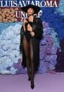<p>teams a black cutout bodysuit with sheer tights, black tuxedo jacket, wide-brim hat and Christian Louboutin heels.</p>